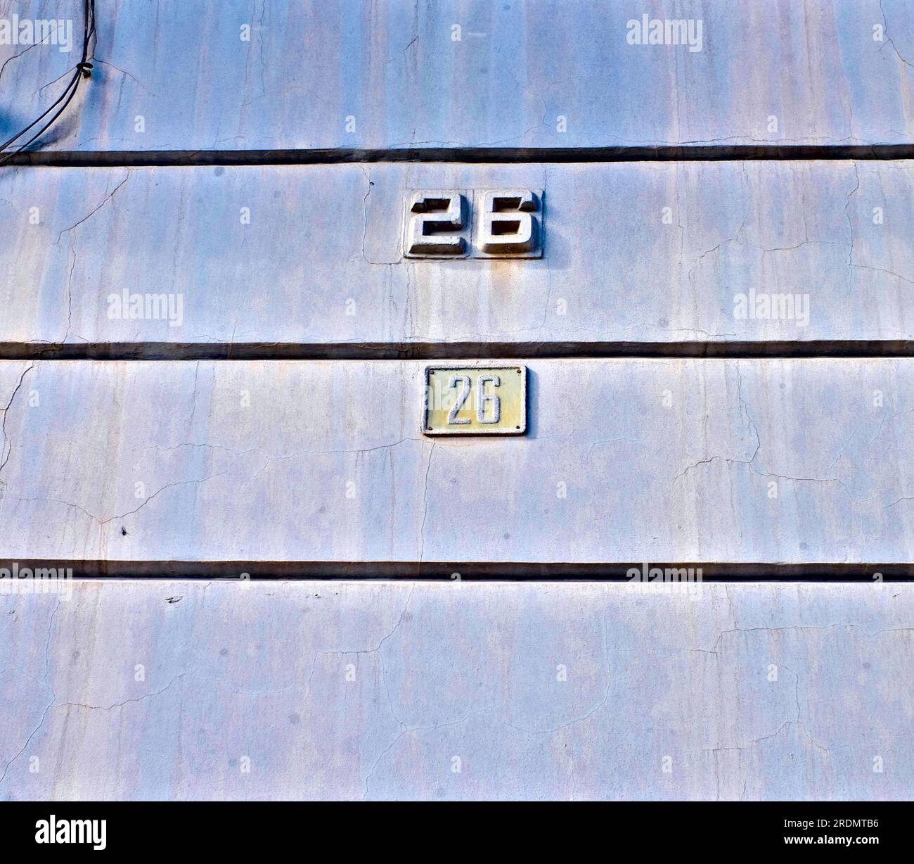 Numéros 26, vingt-six, sur un vieux mur bleu patiné. Banque D'Images