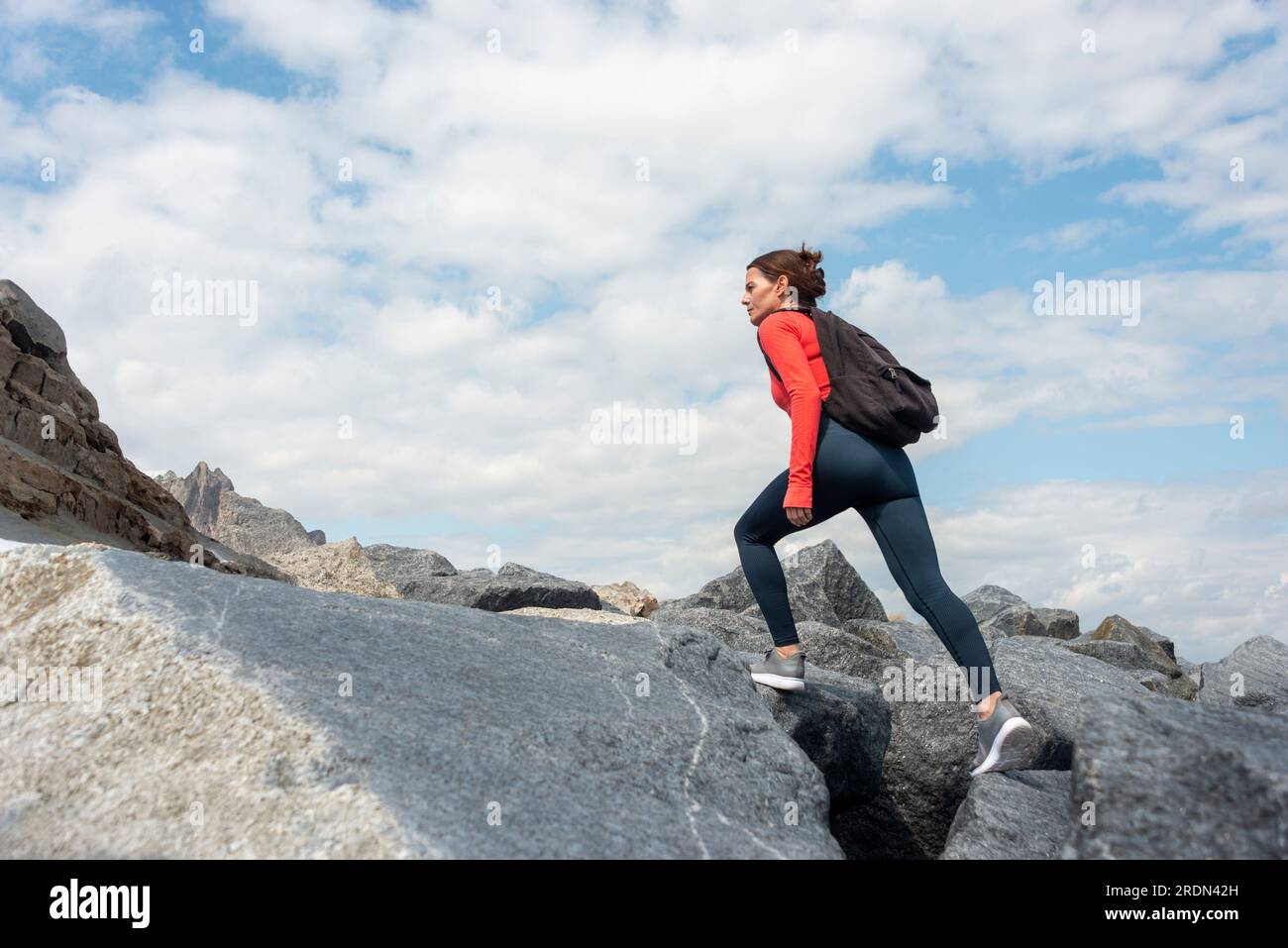 Femme aventureuse marchant jusqu'à une montagne rocheuse. Banque D'Images
