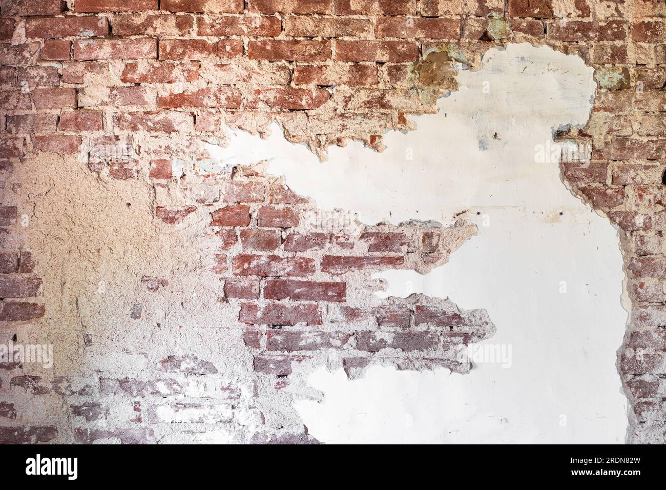 Vieux mur de briques avec plâtre pelant, fond abstrait. Rénovation d'une maison ancienne. Banque D'Images