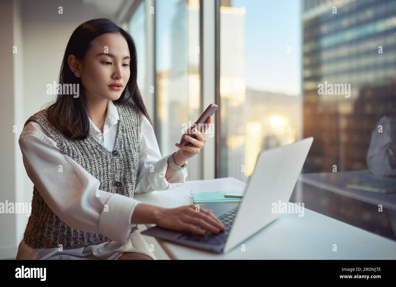 Jeune femme d'affaires asiatique travaillant en utilisant le téléphone et l'ordinateur portable dans le bureau. Banque D'Images