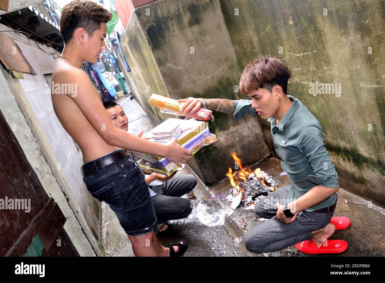 De jeunes Vietnamiens brûlent des offrandes, des papiers joss ou des papiers fantômes pour un ami, nommé Thành Kot, décédé à l'âge de 20 ans. Les papiers Joss sont des papiers fabriqués avec des motifs, des couleurs et des symboles spécifiques pour imiter des objets de valeur tels que l'argent, l'or, les maisons et les voitures. L'acte de les brûler est censé créer un lien avec l'au-delà, envoyant les offrandes aux membres décédés de la famille. Les gens croient que la personne décédée aura une vie meilleure grâce à ce rituel. Banque D'Images