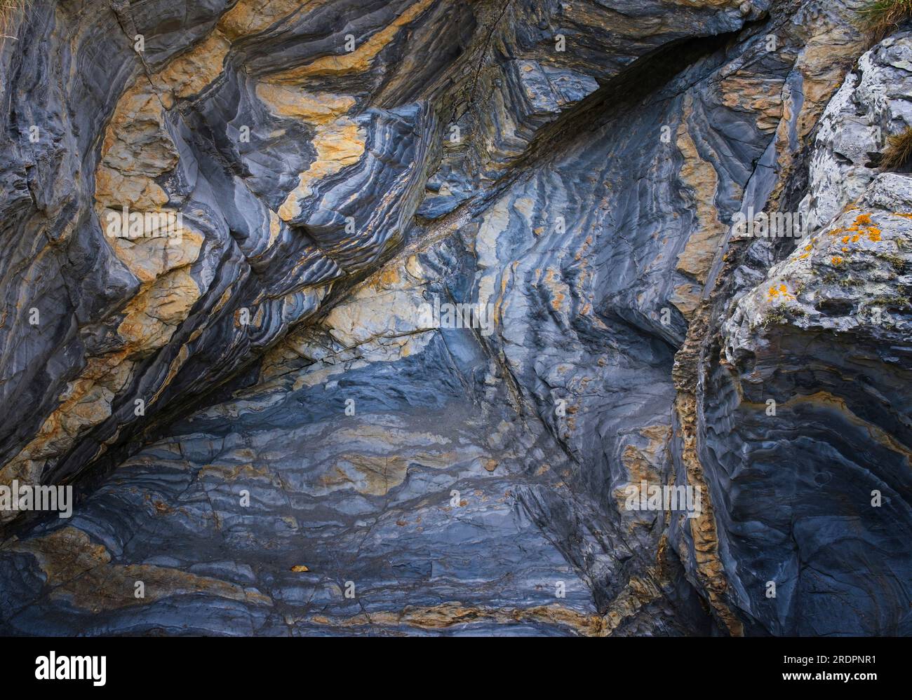 Formation rocheuse dans les tons de bleu et d'orange avec beaucoup de texture et des couches superposées pliées. Banque D'Images