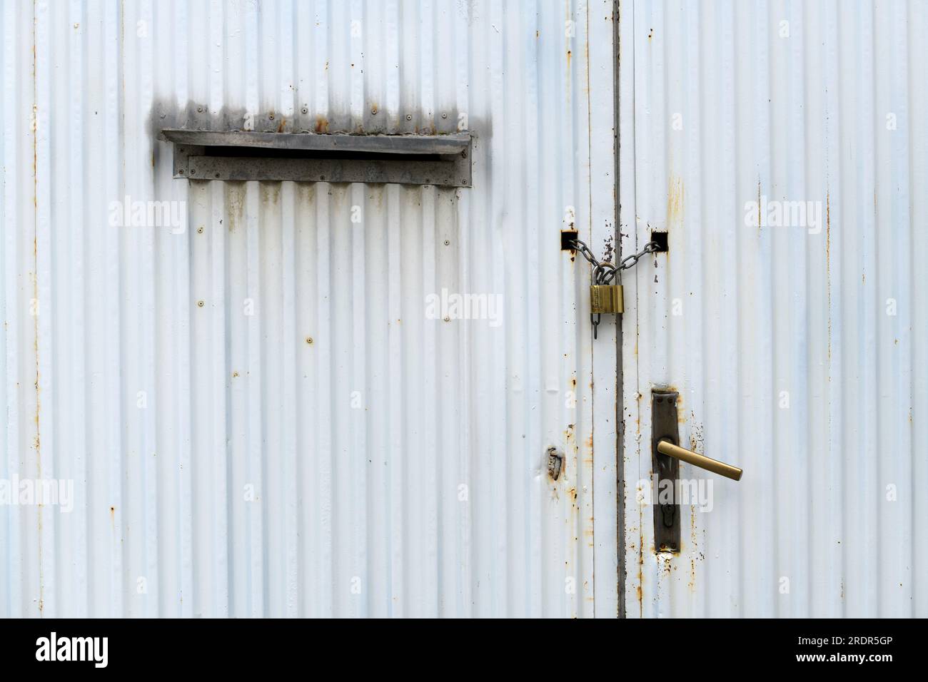 Vieille porte en métal industriel usé avec chaîne et cadenas comme arrière-plan Banque D'Images