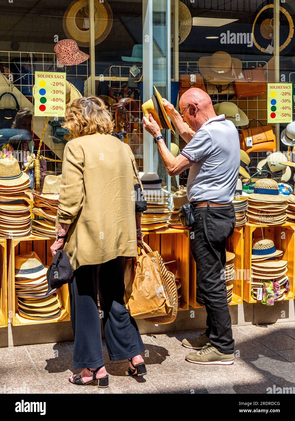Homme essayant des chapeaux de paille en dehors du centre-ville magasin de chapeaux - Loches, Indre-et-Loire (37), France. Banque D'Images