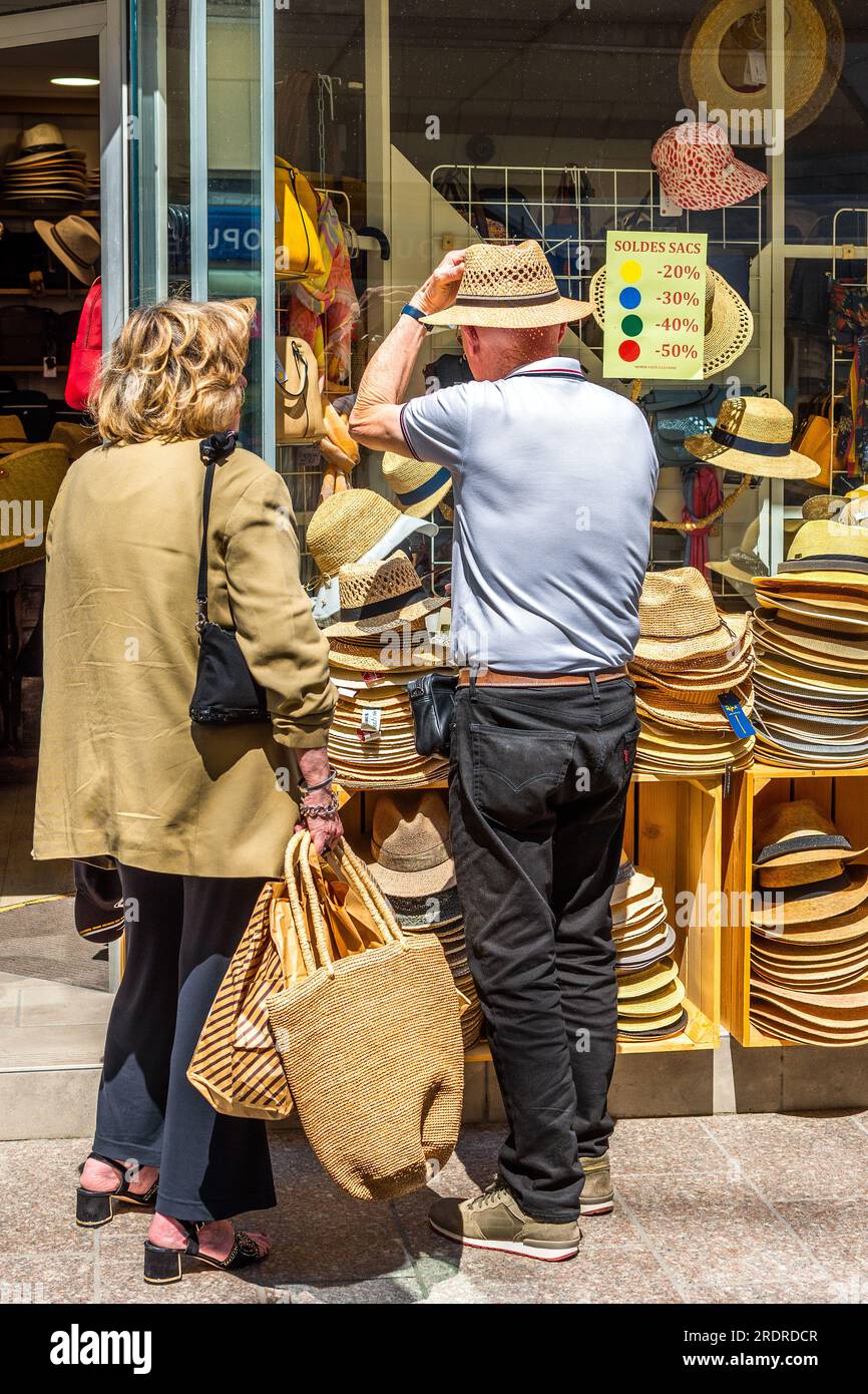Homme essayant des chapeaux de paille en dehors du centre-ville magasin de chapeaux - Loches, Indre-et-Loire (37), France. Banque D'Images