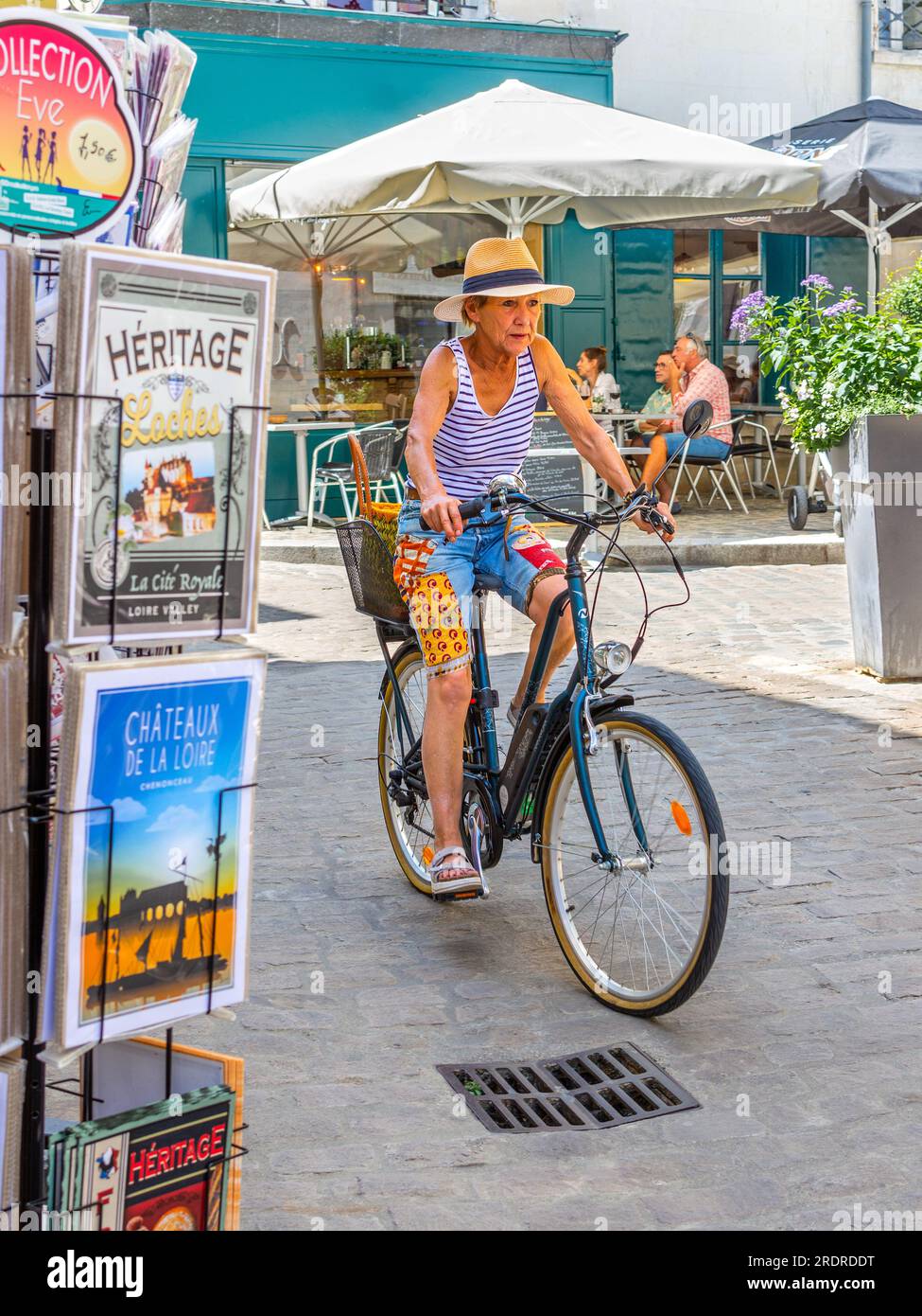 Femme mature, habillée de façon décontractée, vélo sur Nakamura e-bike le long de la rue étroite - Loches, Indre-et-Loire (37), France. Banque D'Images