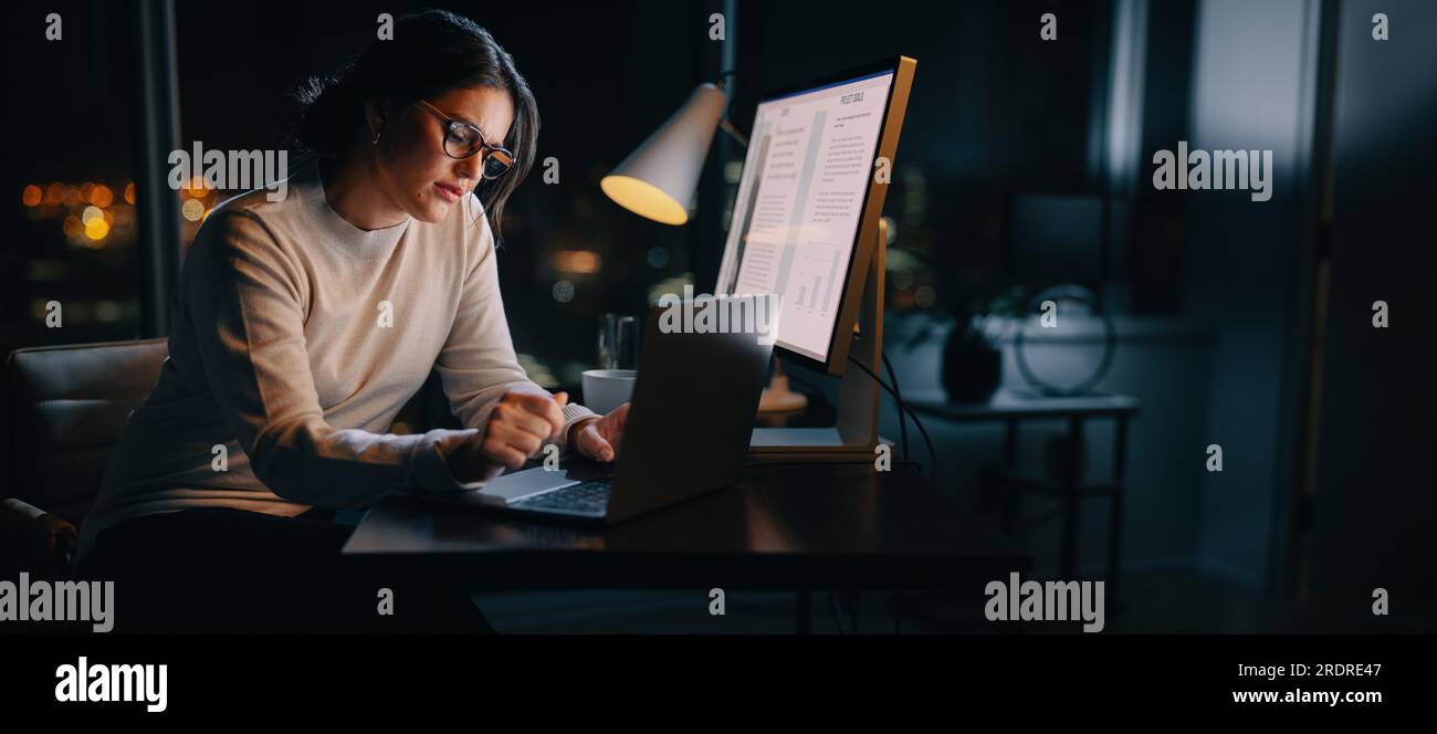 Femme caucasienne travaille tard de son bureau à domicile, tapant ses idées sur son ordinateur portable. Femme d'affaires professionnelle travaillant tard les heures, maintenant un travail-li Banque D'Images