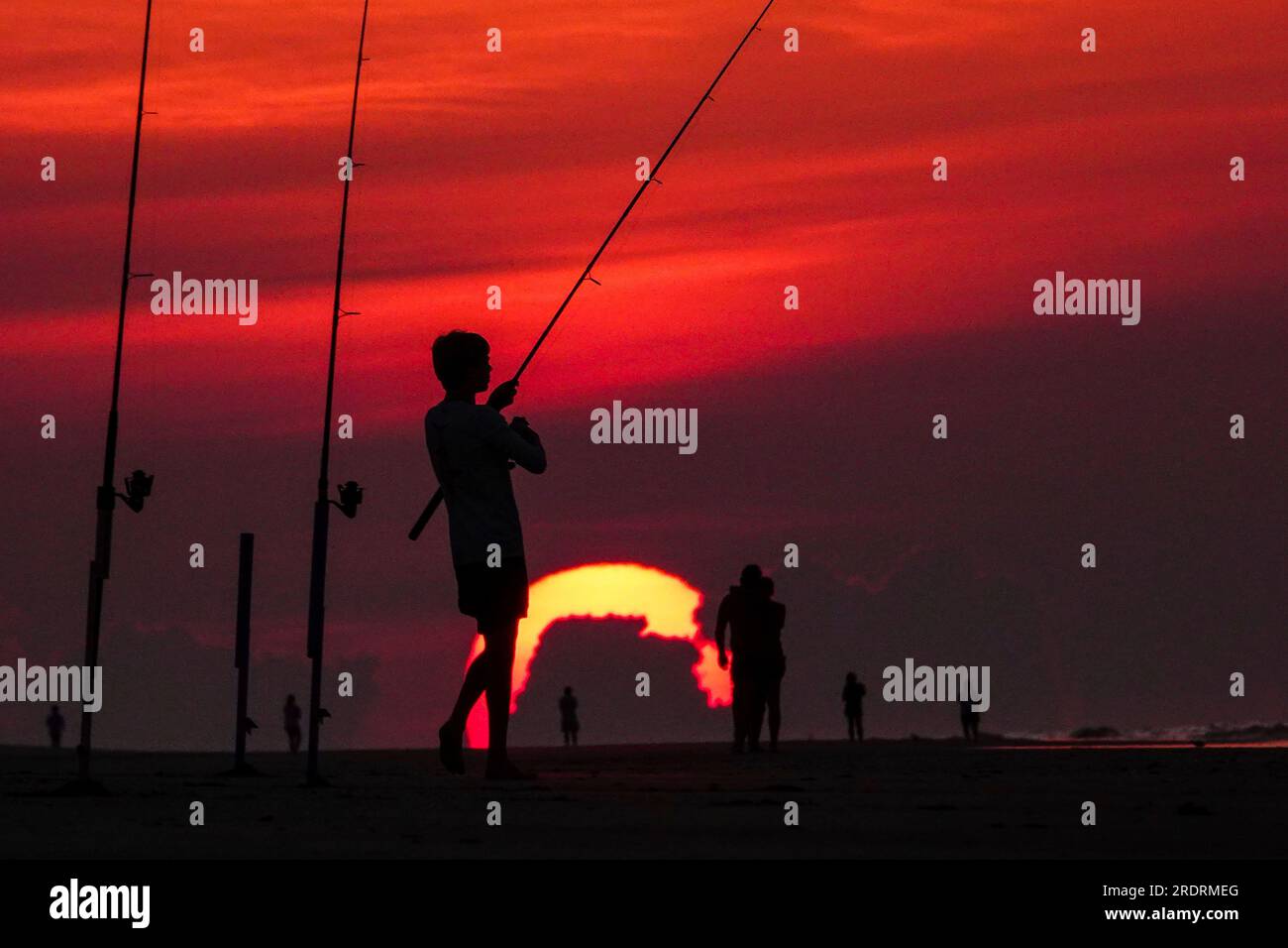 Île de Palms, États-Unis. 23 juillet 2023. Une silhouette de pêcheur face à un lever de soleil dramatique apparaissant comme une boule géante au-dessus de la plage, le 23 juillet 2023 à Isle of Palms, Caroline du Sud. Une vague de chaleur prolongée dans le sud des États-Unis continue d'apporter un temps extrêmement chaud et humide à la région. Crédit : Richard Ellis/Richard Ellis/Alamy Live News Banque D'Images