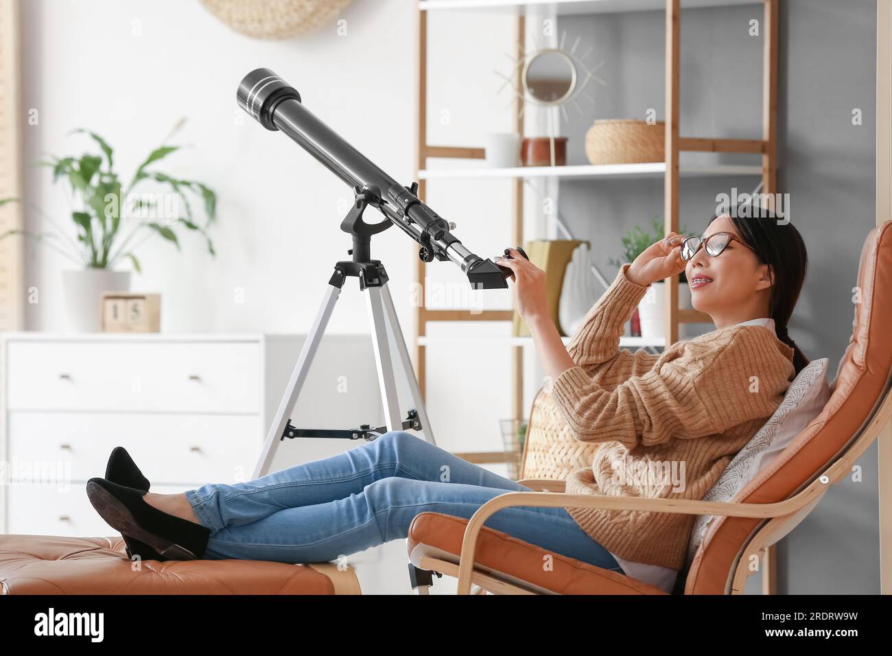 Jeune femme asiatique utilisant le télescope à la maison Banque D'Images