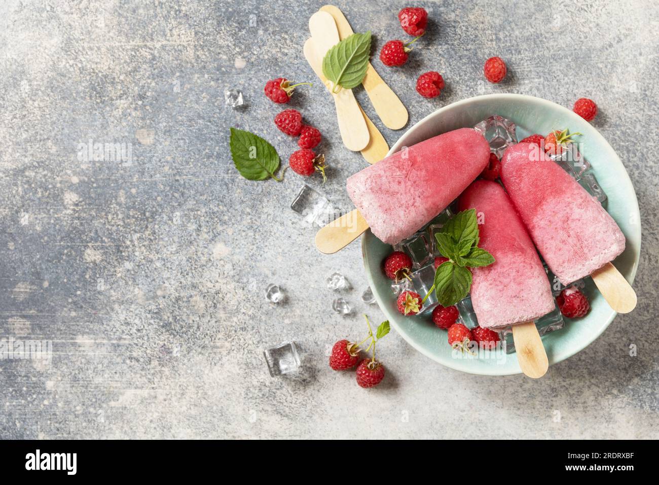 Popsicles de framboise maison avec yaourt et framboises sur un fond de pierre grise. Crème glacée. Dessert d'été. Vue d'en haut. Espace de copie. Banque D'Images