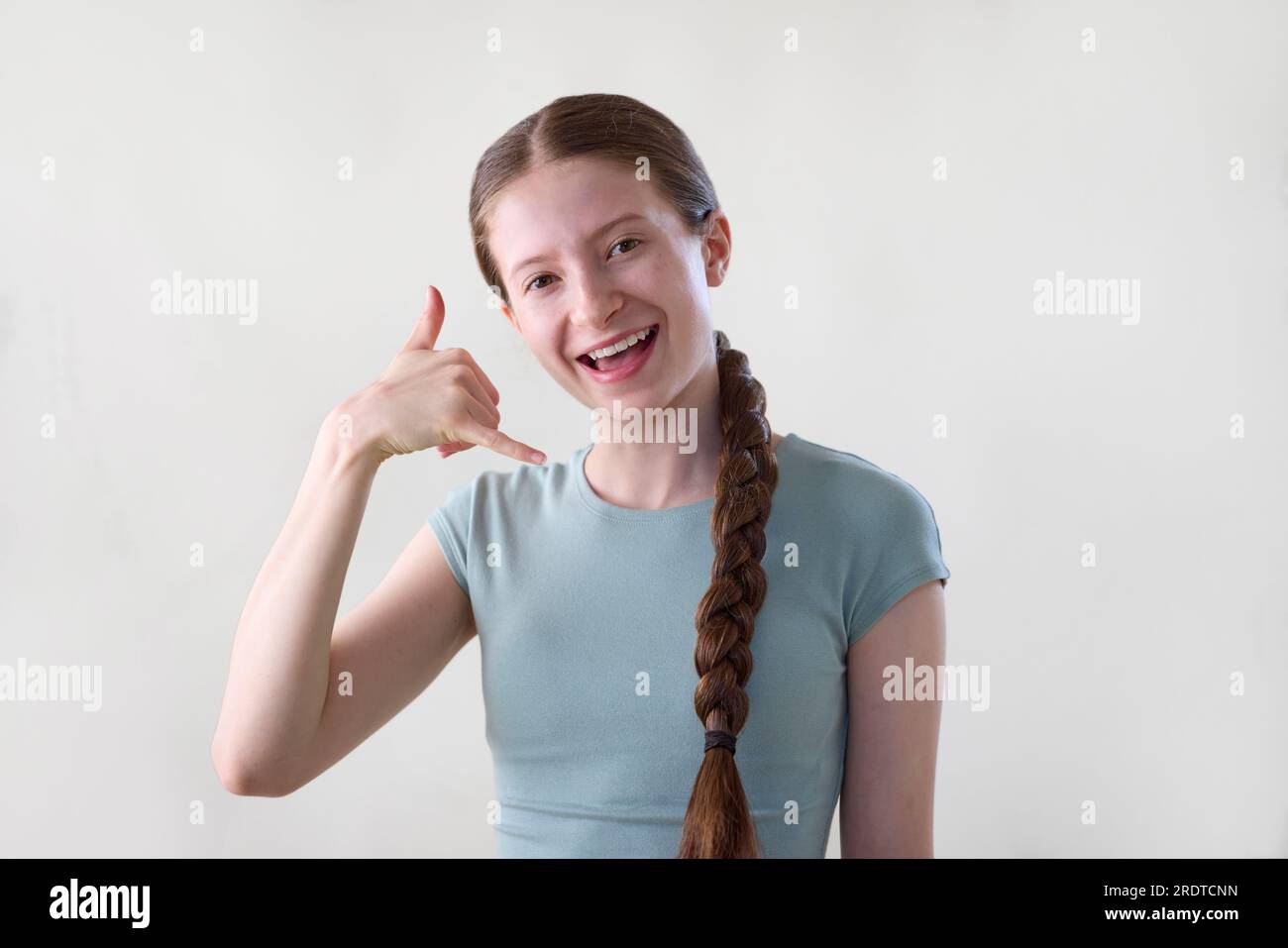 Photo studio de Smiling Teenage Girl Making Call Me Gesture regardant dans la caméra Banque D'Images