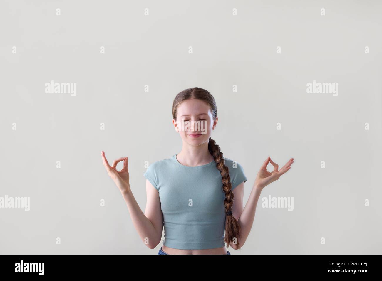Studio Shot de Relaxed Teenage Girl méditant les yeux fermés Banque D'Images