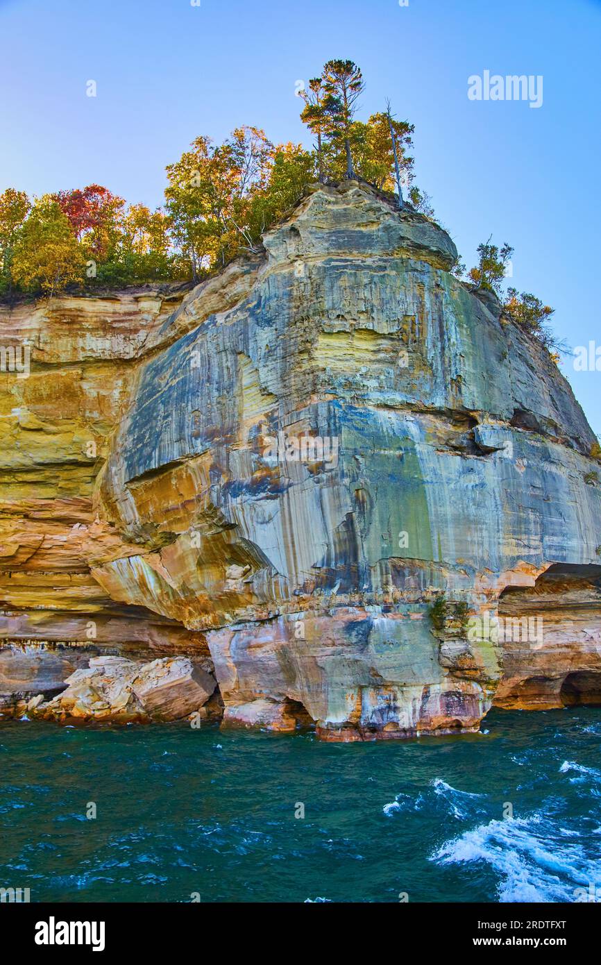Vagues blanches à crête dans les eaux du lac sarcelle sous les rochers représentés face à la falaise avec des arbres de chute Banque D'Images