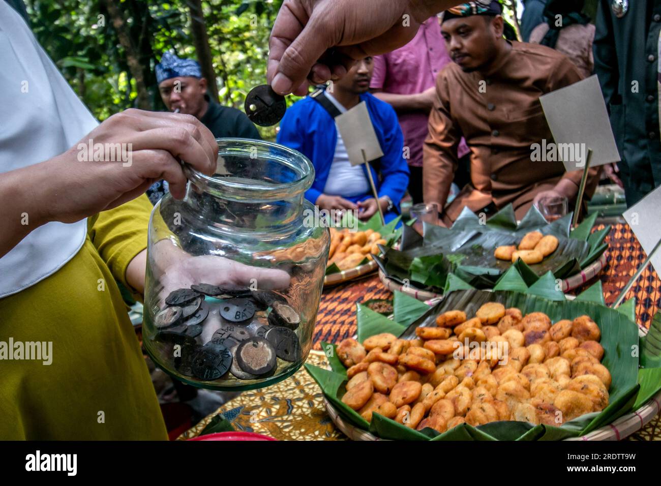 Les acheteurs paient pour des collations de manioc frit avec des chips de coquille de noix de coco valant une coquille comme moyen de paiement au lieu d'argent lors d'un festival de snack de village Banque D'Images