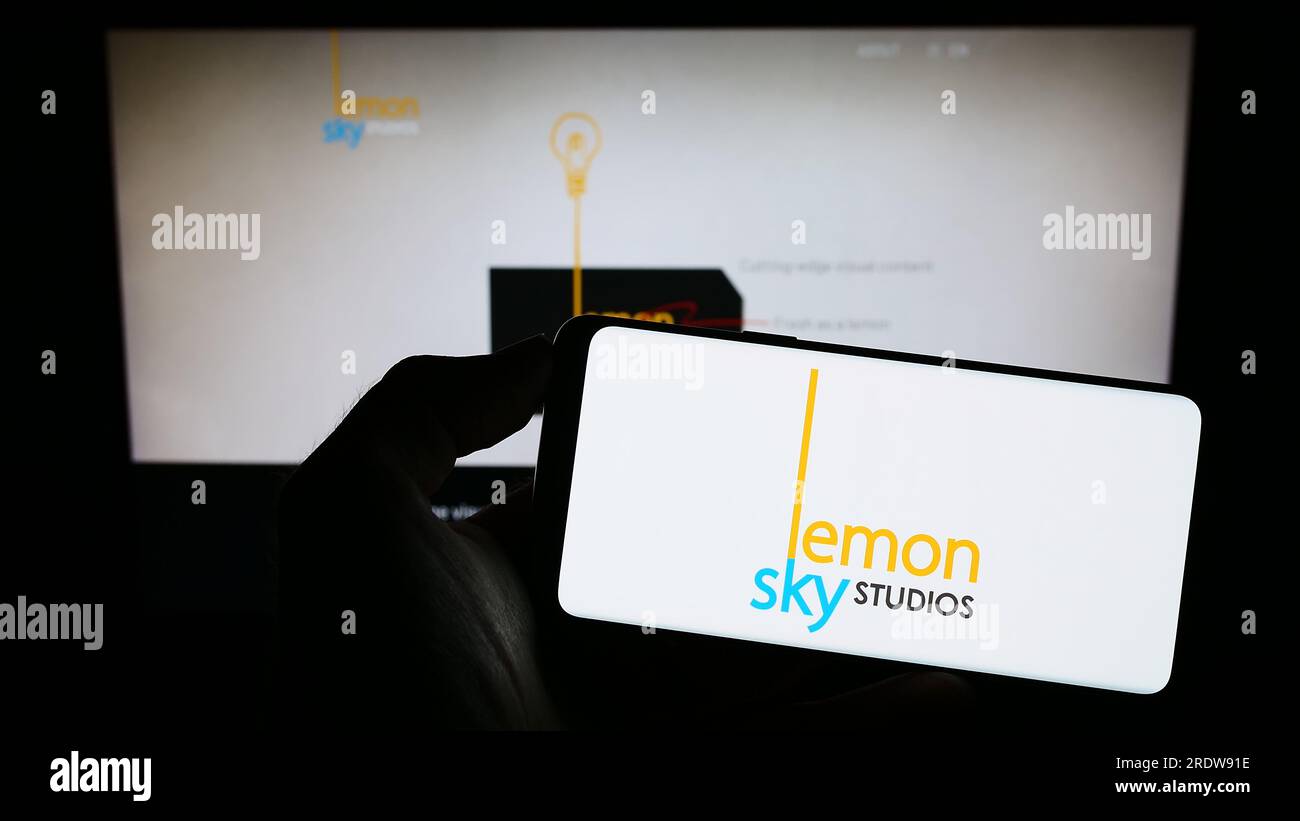 Personne tenant le téléphone portable avec le logo de la société malaisienne de jeux vidéo Lemon Sky Studios sur l'écran devant la page Web. Concentrez-vous sur l'affichage du téléphone. Banque D'Images