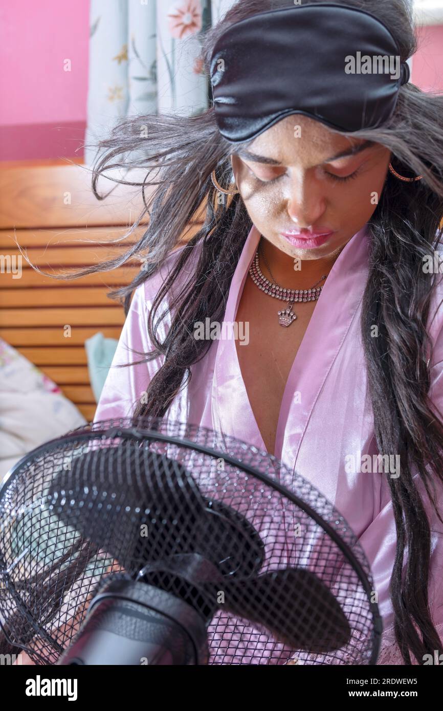 Jolie fille avec insomnie essayant de se rafraîchir et de dormir dans la canicule par temps chaud Banque D'Images