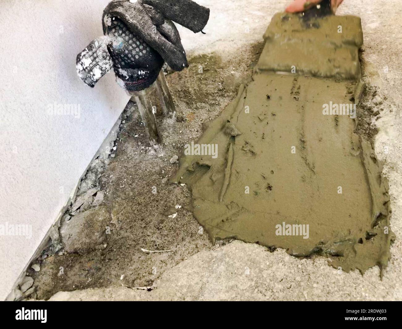 Les mains du constructeur avec une spatule en métal plâtre le mur, verse la chape avec du plâtre, de la colle pour carreaux, du ciment pour la réparation de l'appartement, la construction d'un Hous Banque D'Images