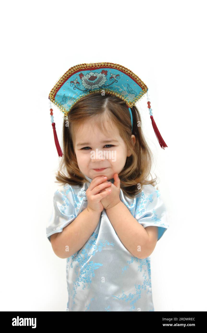 Petite fille rigole avec amusement comme elle porte un dess de style kimono avec casque assorti. Elle a les cheveux longs et tient ses mains sous son f Banque D'Images