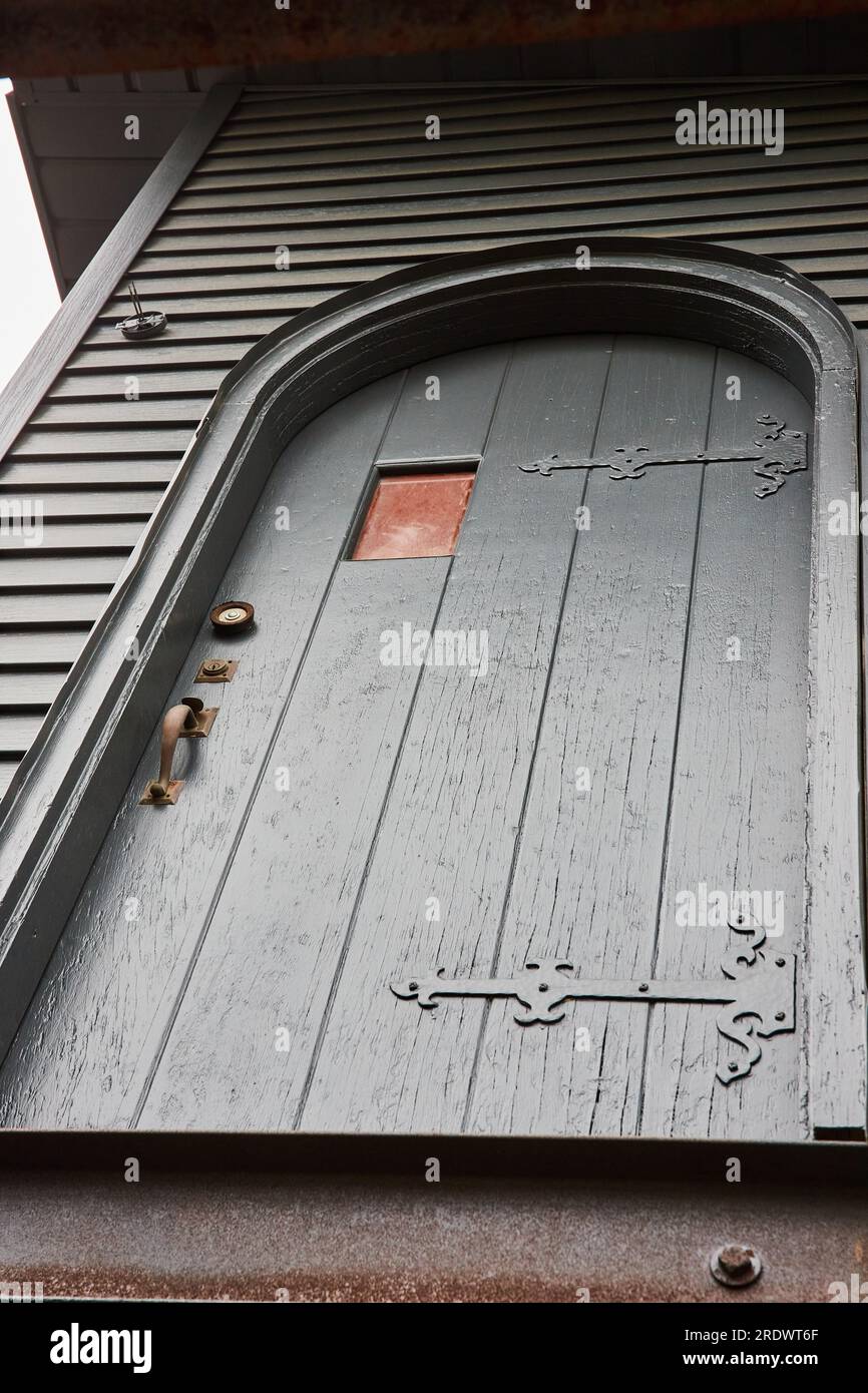 Propriétaire spécial sur la vieille porte en bois avec des accents en métal fermer avec le revêtement de maison de la même couleur que la porte Banque D'Images