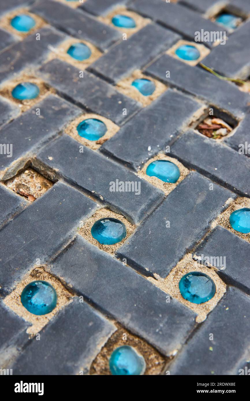 Vue rapprochée du chemin avec des briques noires alternées avec des pierres de marbre bleu variables et manquantes Banque D'Images
