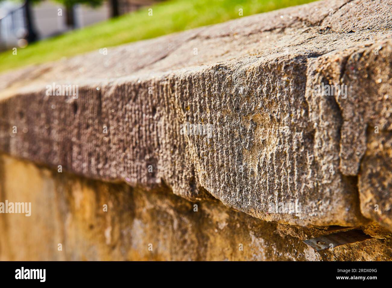Gros plan du mur de béton usé par les intempéries avec de l'herbe au-dessus Banque D'Images