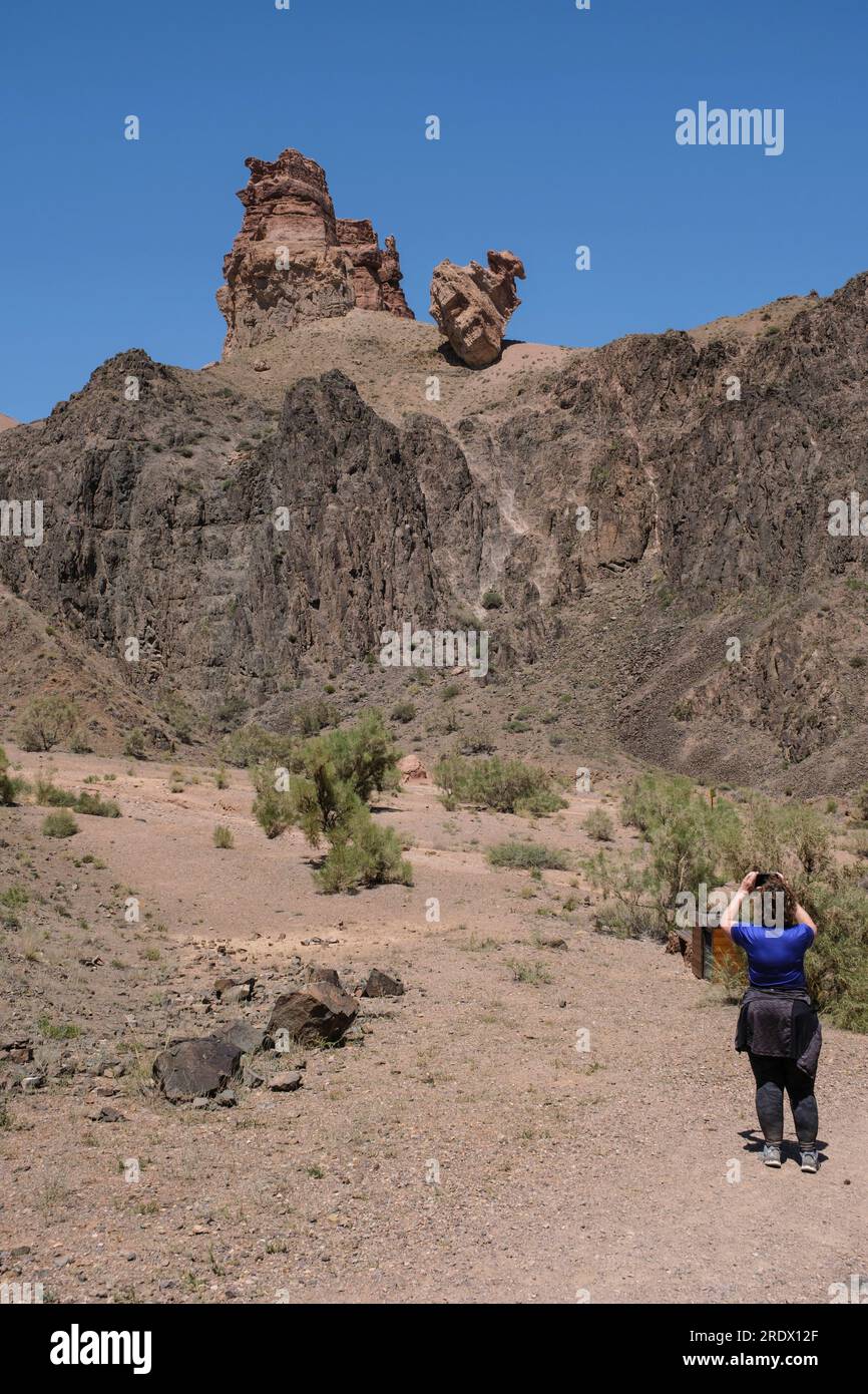 Kazakhstan, Canyon de Charyn (Sharyn). Visiteur photographiant un rocher perché de façon précaire depuis le Canyon Trail. Banque D'Images