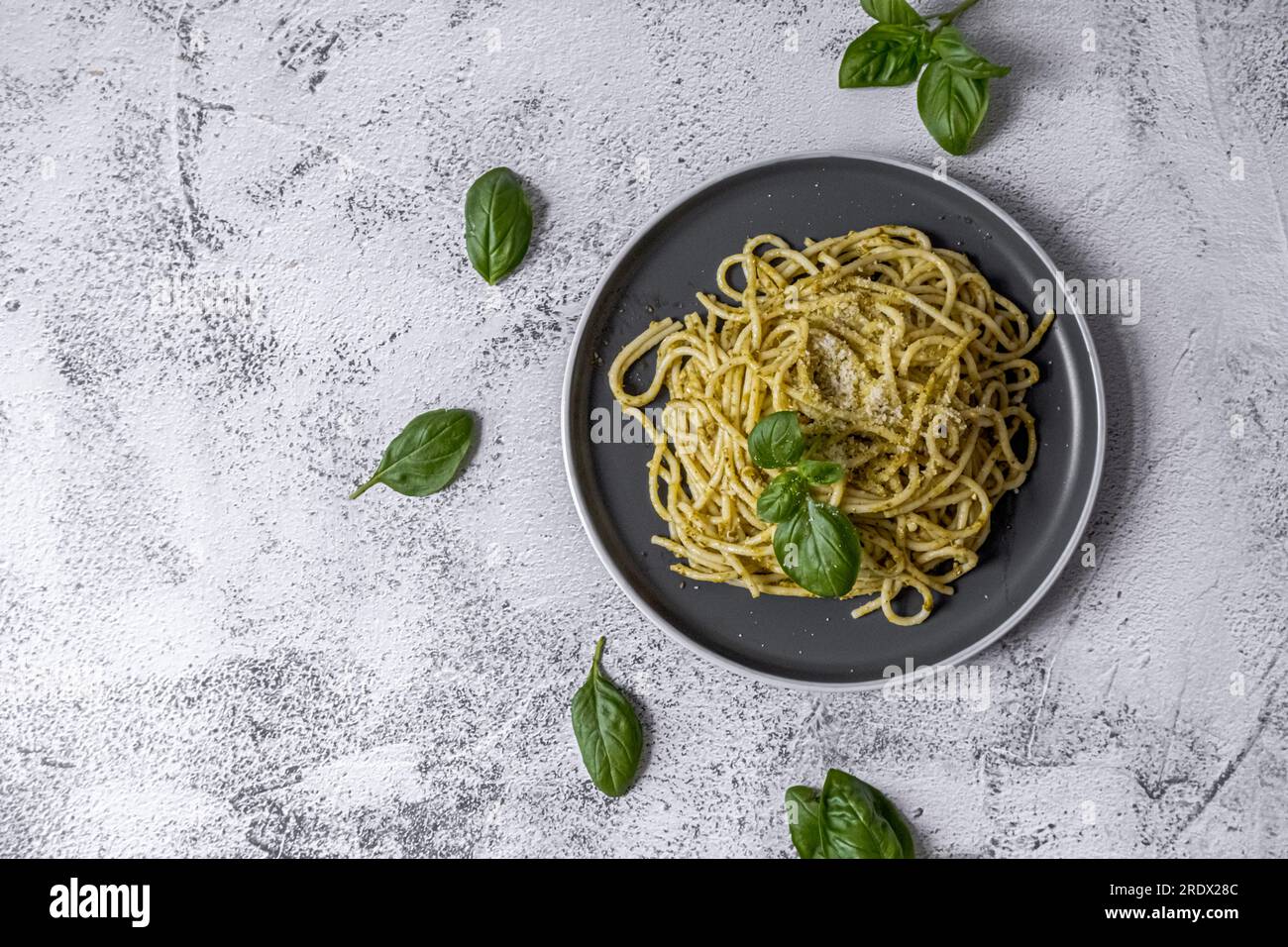 Pâtes spaghetti avec sauce pesto et feuilles de basilic frais dans un bol gris. Vue de dessus. Banque D'Images