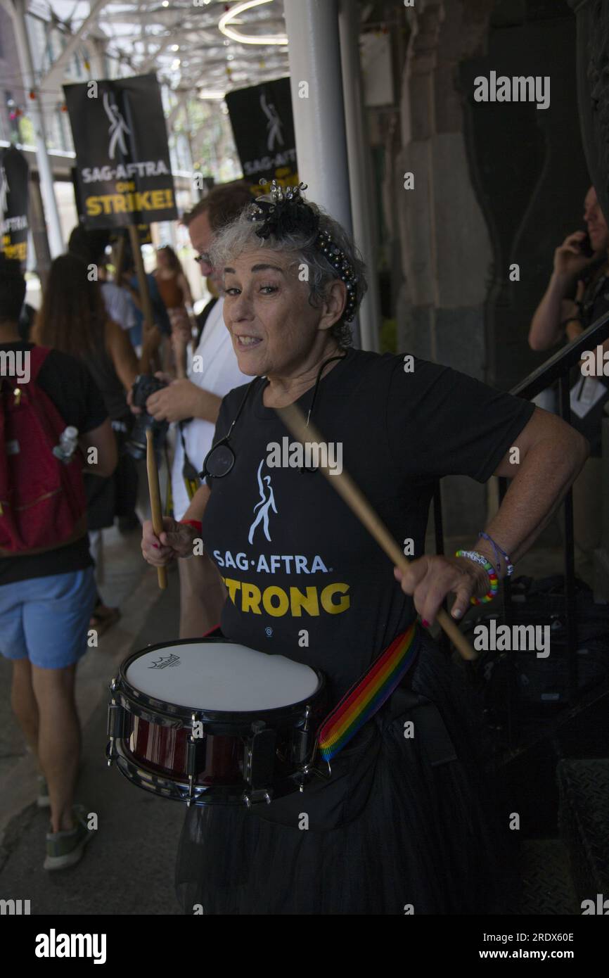 New York City : la grève se poursuit parmi les Writers Guild of America et les membres du syndicat SAG-AFTRA avec des lignes de piquetage dans plusieurs endroits à Manhattan. Une femme bat un tambour devant Warner Bros. Banque D'Images