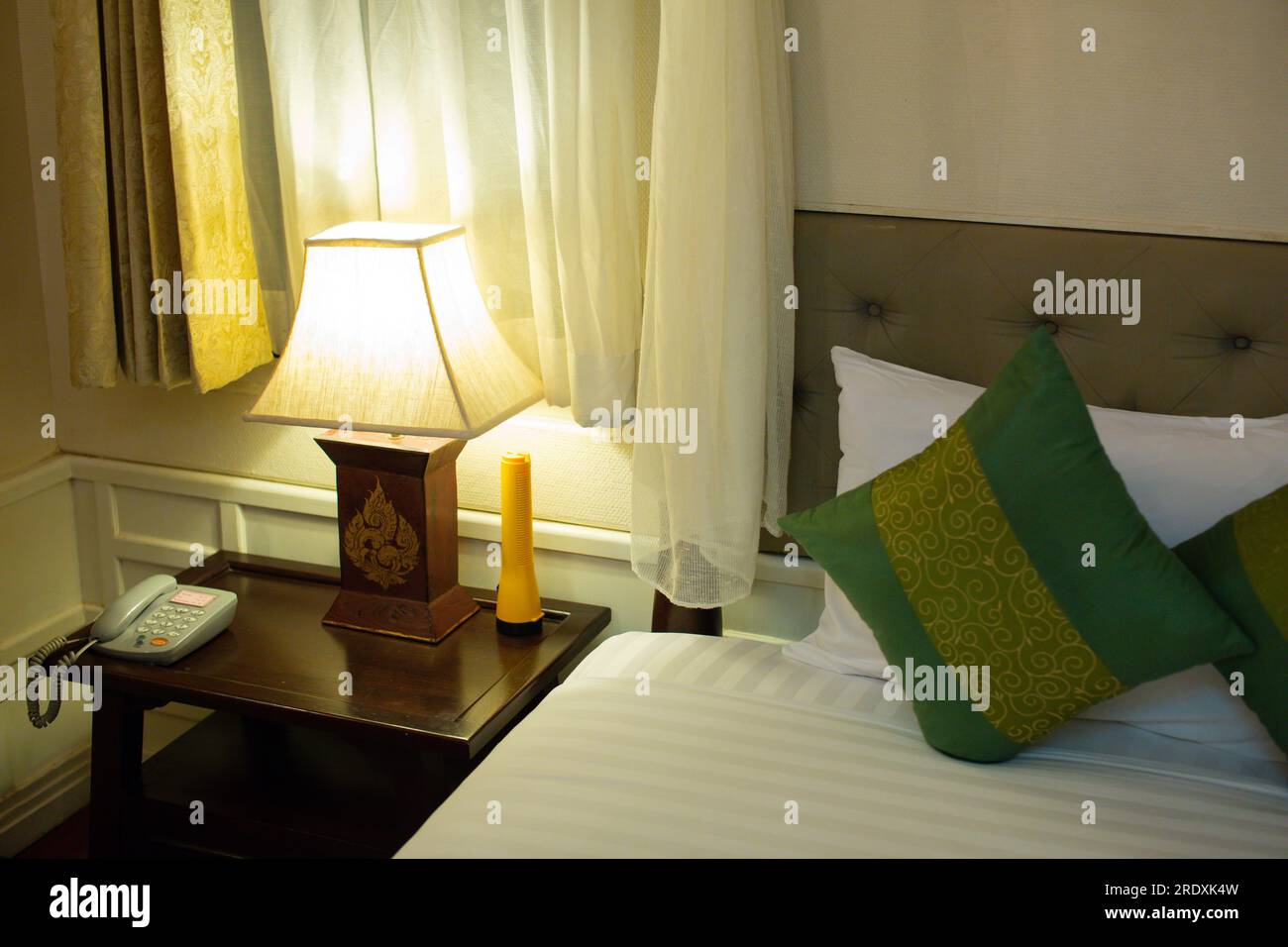 Lit avec couvertures et oreillers avec lampe électrique sur la table de chevet dans la chambre. Design de chambre simple et confortable pour la vie quotidienne. Horizontal Banque D'Images
