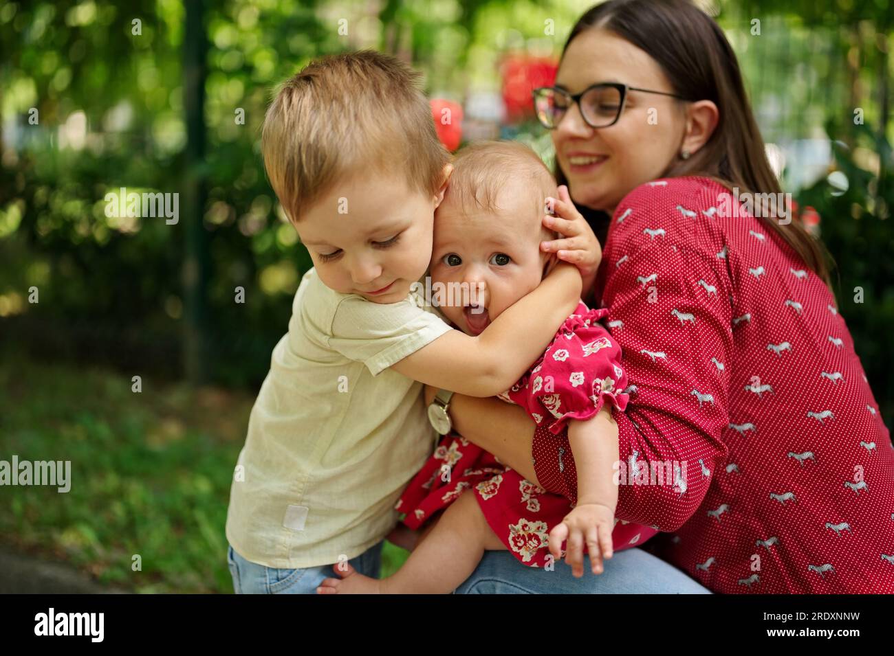 Mère et deux enfants câlinés dans un parc Banque D'Images