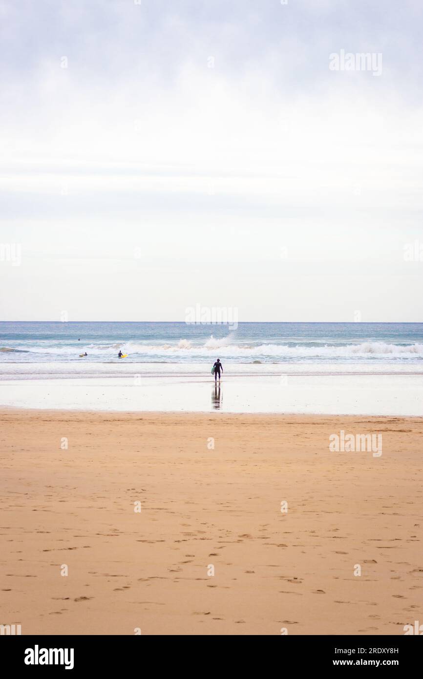 Surfeurs sur large plage, baie de Biscaye. Concept de surf. Personnes actives. Journée de surf idyllique en Espagne. Seascape avec vagues et surfeurs. Mode de vie actif. Banque D'Images