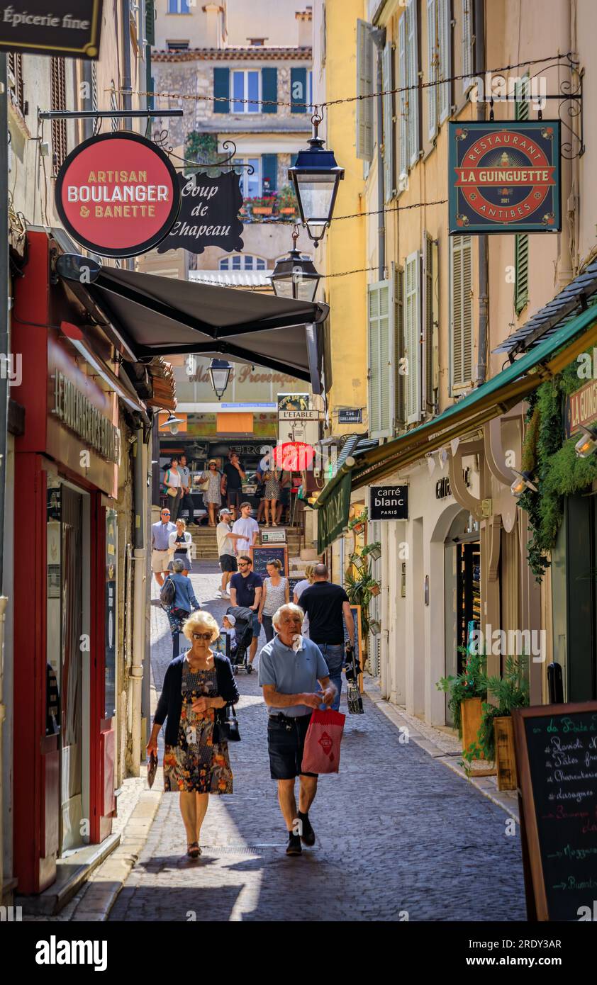Antibes, France - 24 mai 2023 : les gens marchent entre les magasins dans les vieilles maisons dans une rue près du marché provençal couvert local dans la vieille ville Banque D'Images