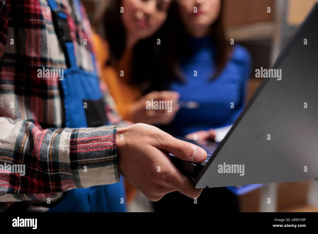 Employés de magasin utilisant un ordinateur portable tout en travaillant dans la salle de stockage. Les gestionnaires asiatiques d'entrepôt et l'équipe de manutention de colis gèrent l'exécution des commandes avec gros plan sur l'ordinateur portable Banque D'Images