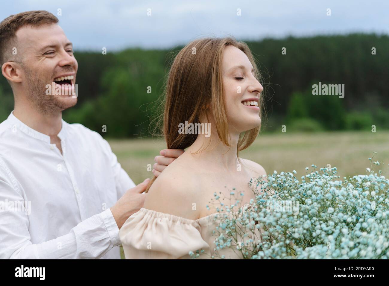 Homme joyeux jouant avec les cheveux de la petite amie sur le terrain Banque D'Images