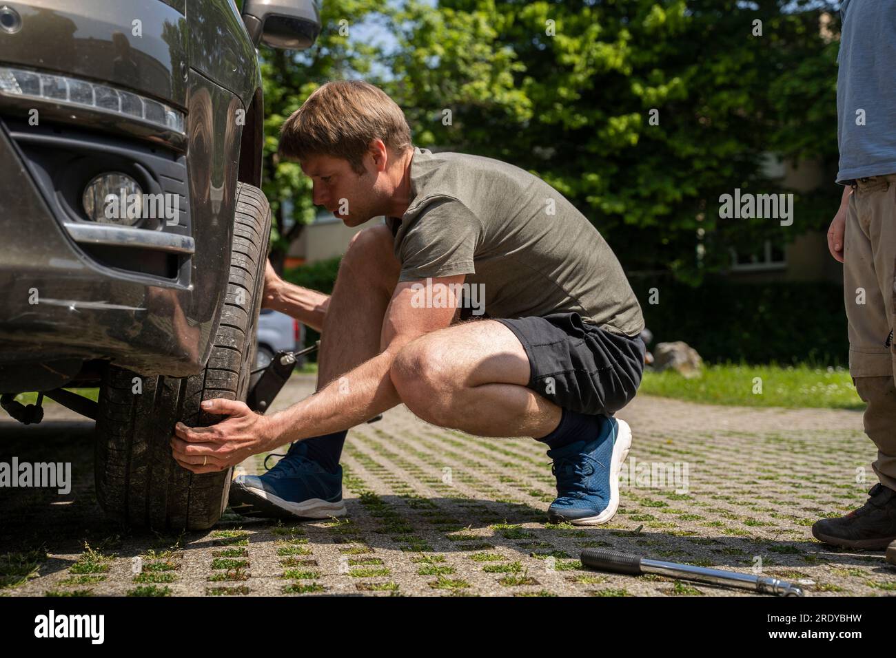 Homme changeant le pneu de voiture dans la cour Banque D'Images