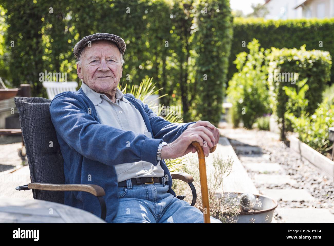 Homme âgé souriant portant un béret assis dans un fauteuil Banque D'Images