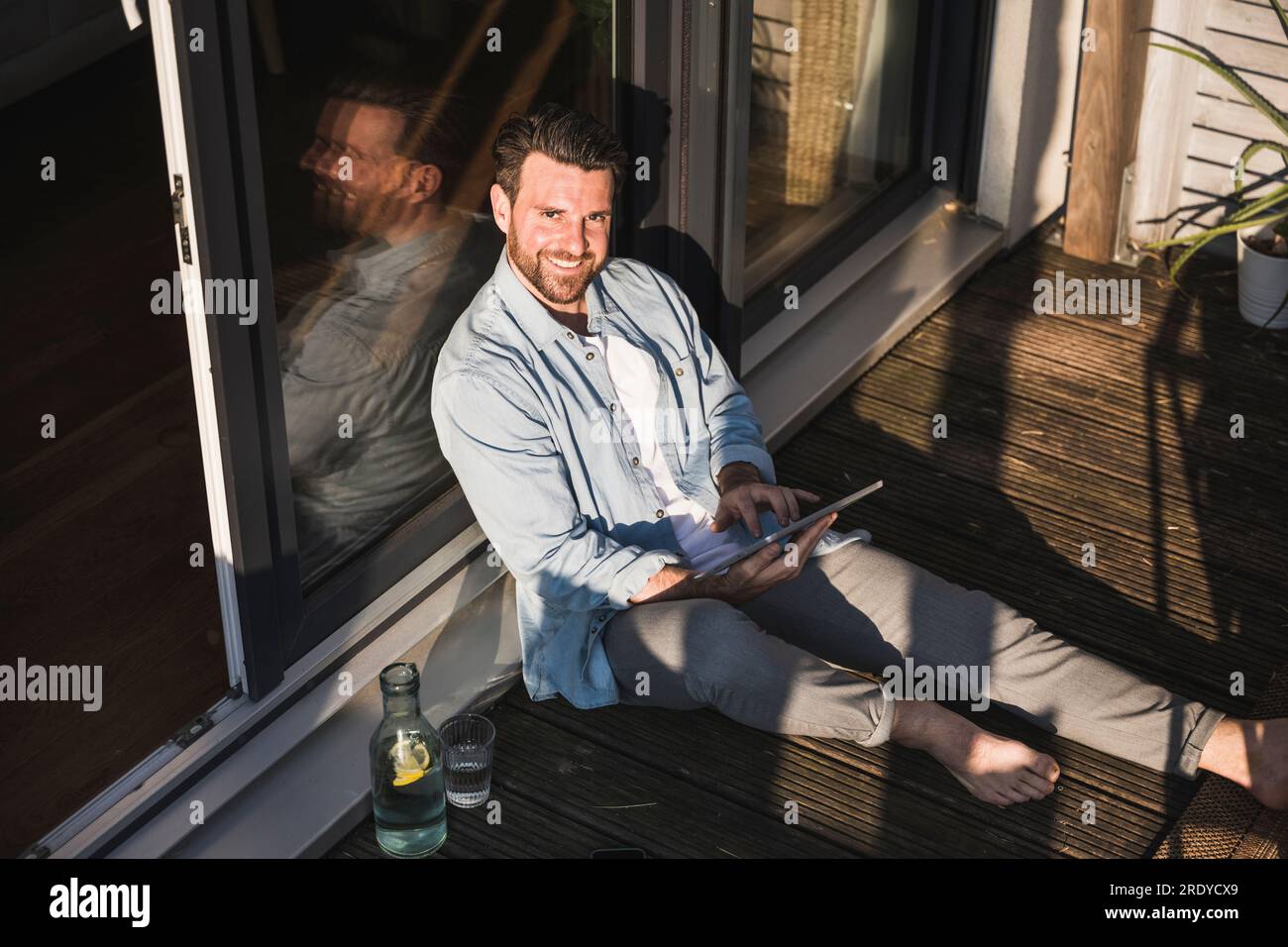 Heureux freelancer assis avec tablette PC sur le porche Banque D'Images