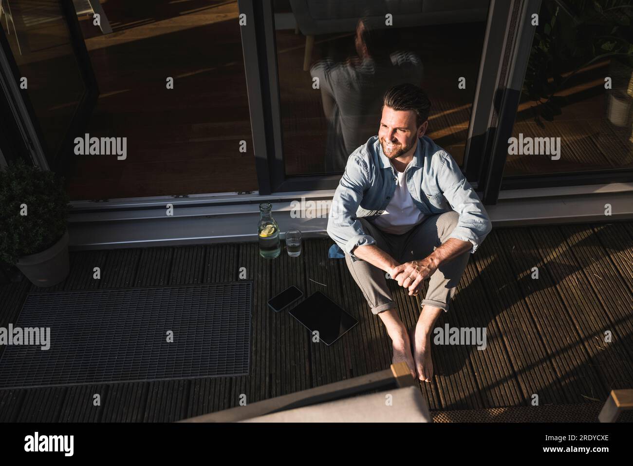 Pigiste réfléchi assis avec les mains serrées sur le porche Banque D'Images