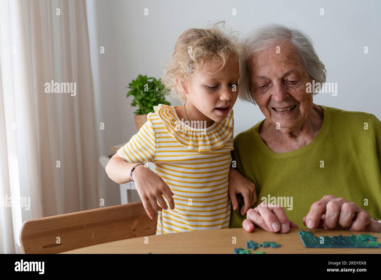 Grand-mère enseignant petite-fille pour résoudre puzzle à la maison Banque D'Images