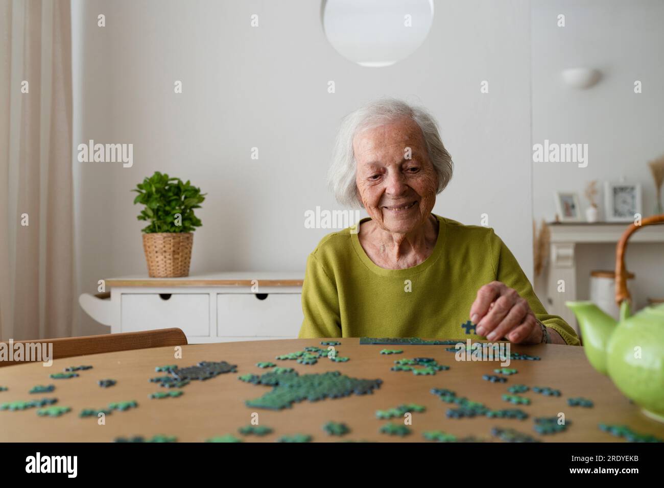 Femme senior résolvant puzzle à la maison Banque D'Images