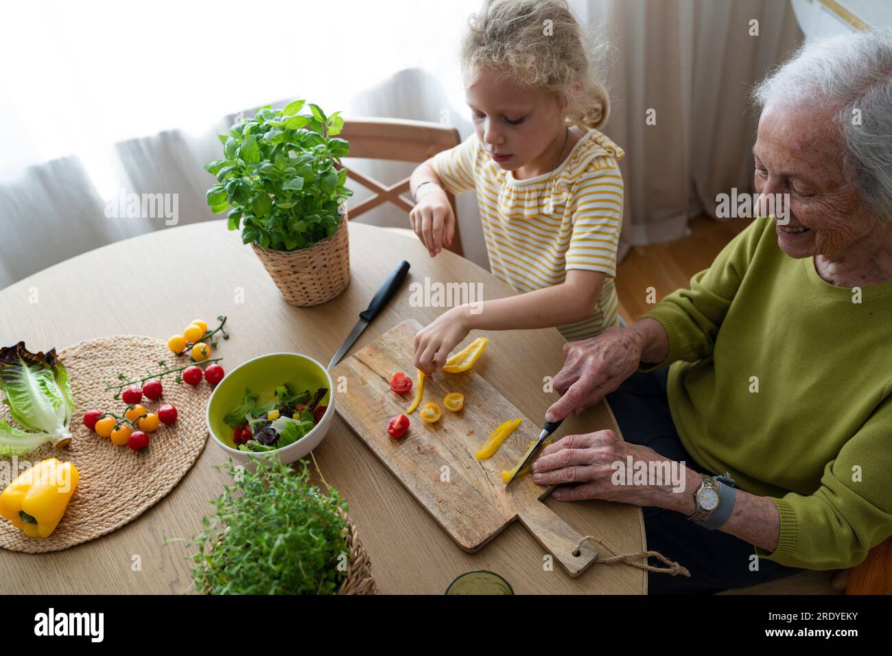 Grand-mère et petite-fille souriantes coupant des légumes à la maison Banque D'Images