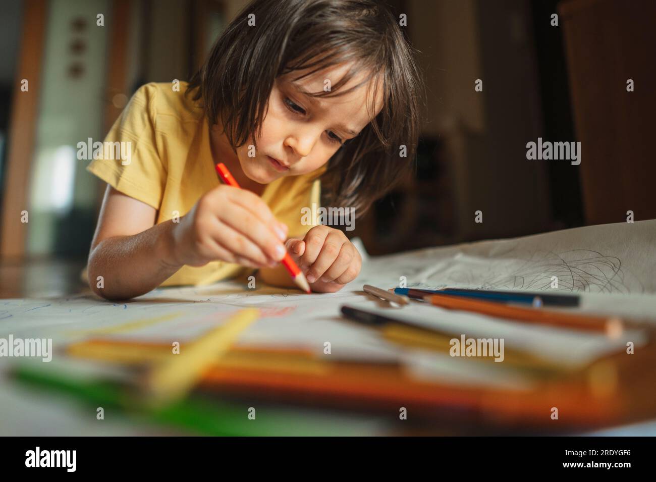 Dessin de garçon concentré avec un crayon de couleur à la maison Banque D'Images