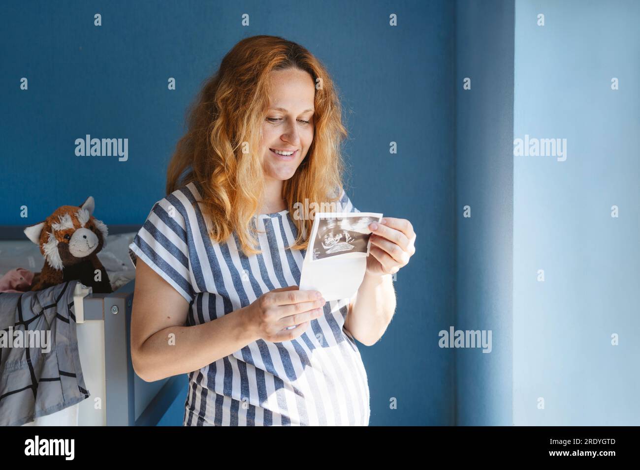 Femme enceinte heureuse regardant les images échographiques Banque D'Images