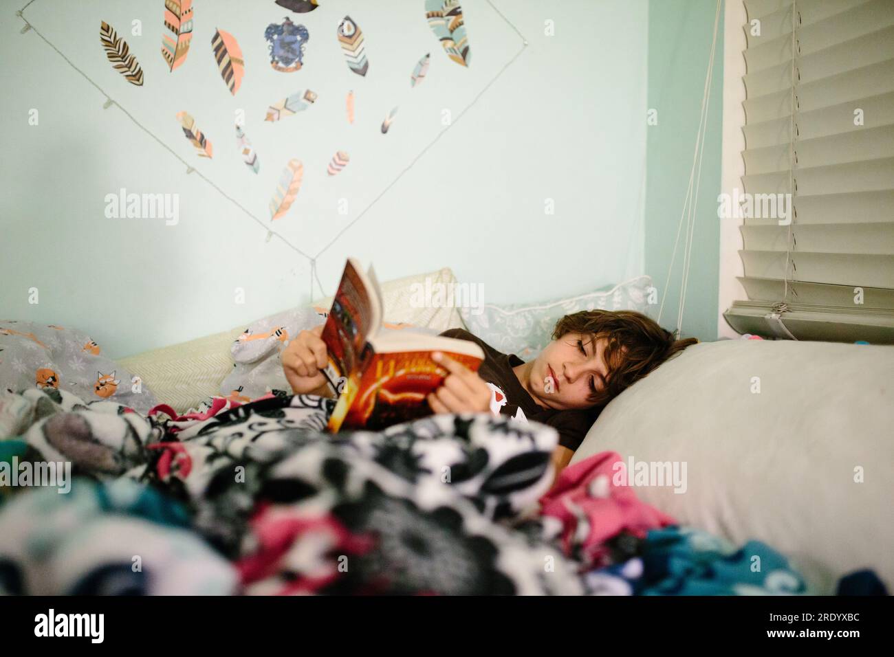 Adolescente allongée dans son lit lisant un livre avant le coucher Banque D'Images