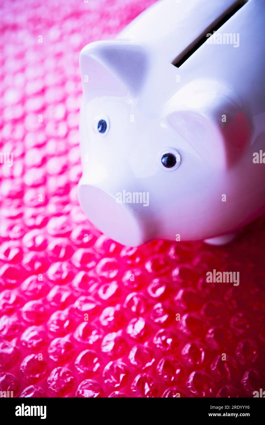 Tirelire en porcelaine blanche sur papier bulle rouge Banque D'Images