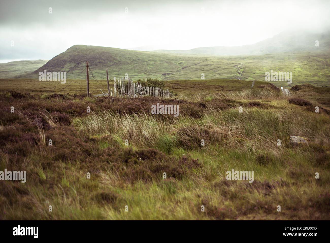Une vieille clôture rustique brisée traverse des montagnes brumeuses éloignées Banque D'Images