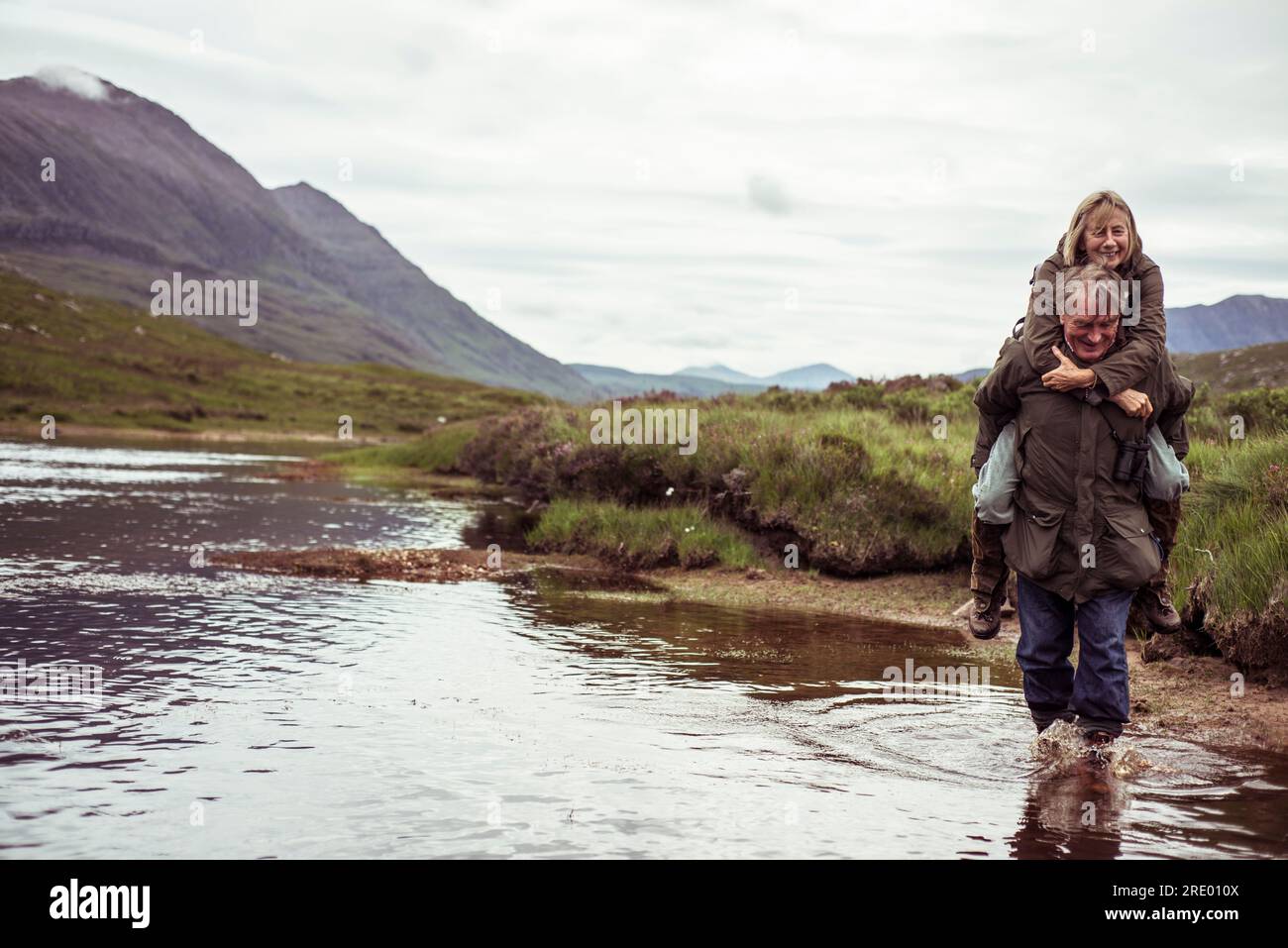 un couple retraité de cochon porte à travers une rivière de pêche de montagne isolée Banque D'Images