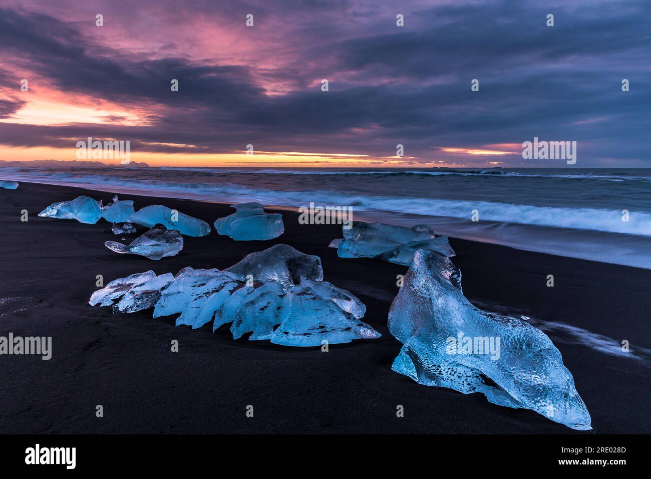 Coucher de soleil, plage de sable noir et morceaux de glace en Islande Banque D'Images