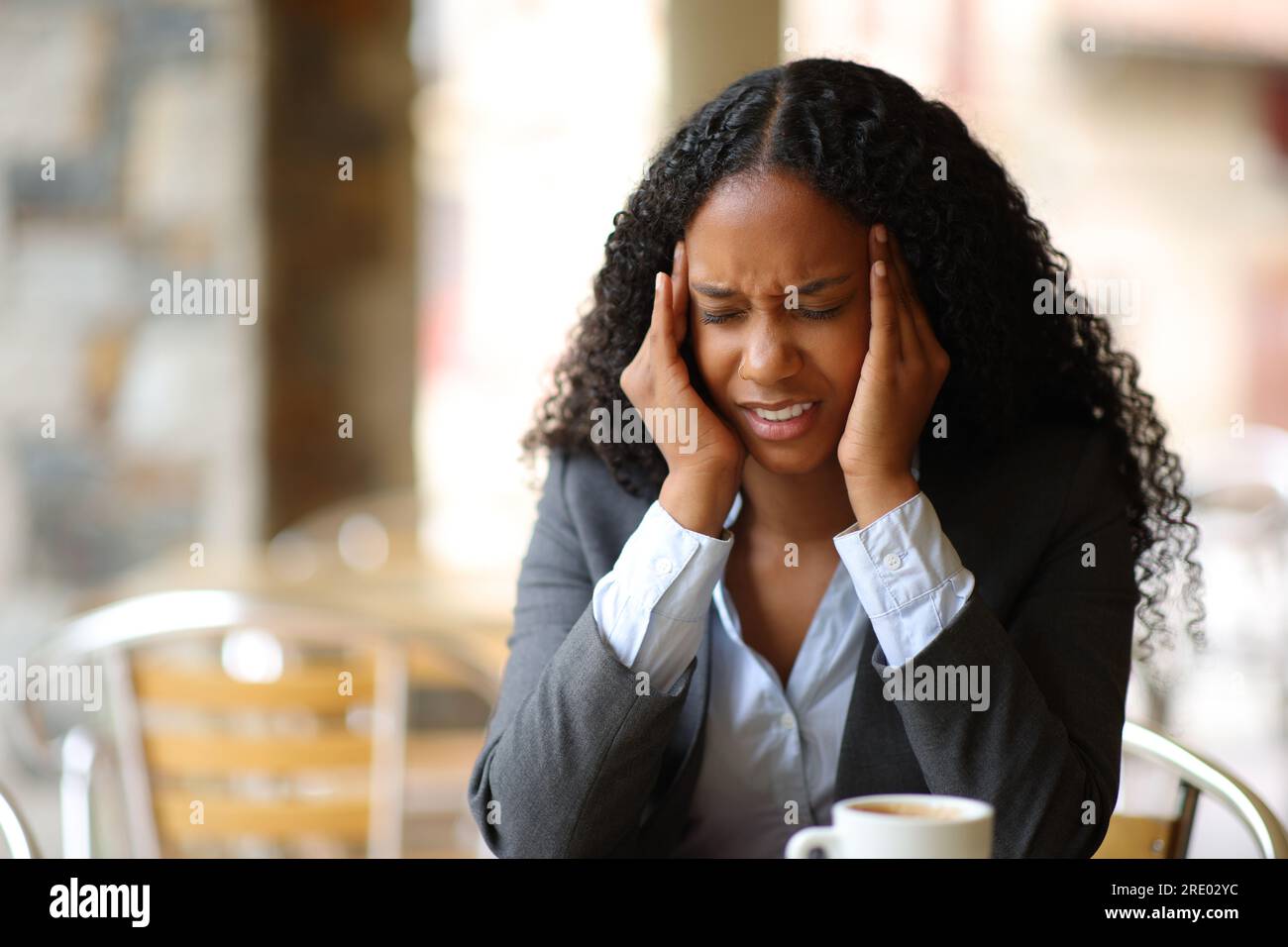 Femme d'affaires noire souffrant de migraine se plaignant dans une terrasse de bar Banque D'Images