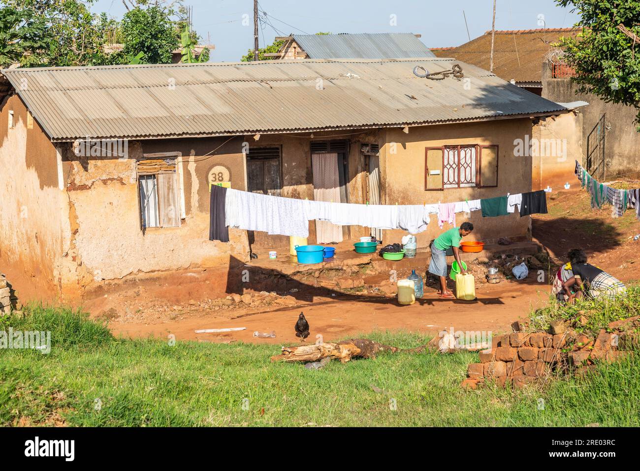 Maison individuelle dans la banlieue d'Entebbe, Ouganda. Les dames font la lessive. Banque D'Images